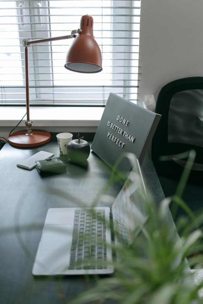 A Laptop on a Work Desk Beside a Plant